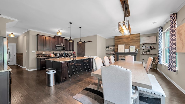 dining area with sink, a barn door, crown molding, and dark wood-type flooring