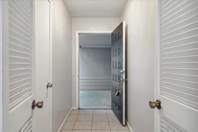 hall featuring a textured ceiling and light tile patterned flooring