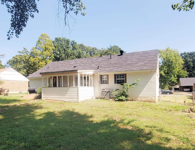 back of house with a sunroom, a lawn, fence, and brick siding