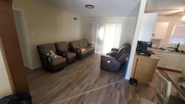 living area with light wood finished floors, a ceiling fan, and visible vents