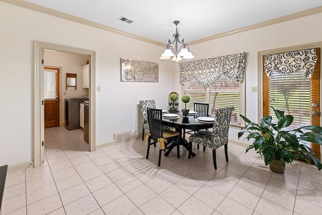 tiled dining space featuring ornamental molding, an inviting chandelier, and washer and clothes dryer