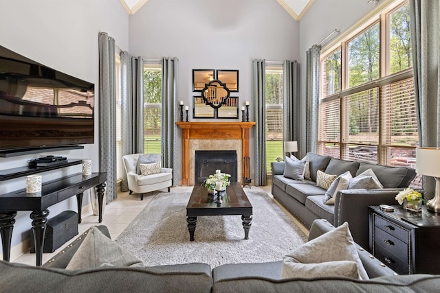 living room featuring a tile fireplace, crown molding, high vaulted ceiling, and a wealth of natural light