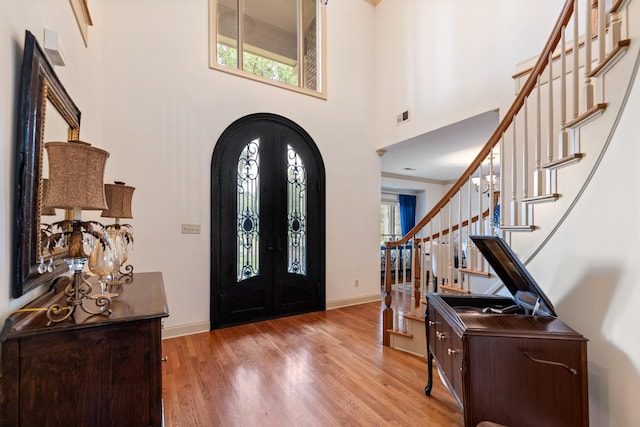 foyer featuring french doors, light hardwood / wood-style flooring, a high ceiling, and a wealth of natural light