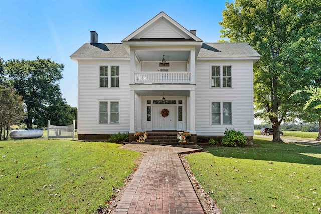 view of front of house featuring a balcony and a front lawn