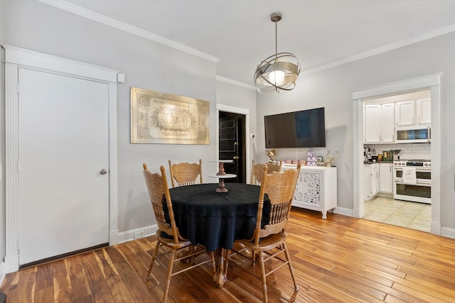 dining space with ornamental molding and light wood-type flooring