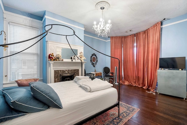 bedroom featuring dark hardwood / wood-style floors, a textured ceiling, an inviting chandelier, and a fireplace