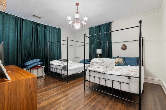 bedroom featuring ornamental molding, dark wood-type flooring, a notable chandelier, and a textured ceiling