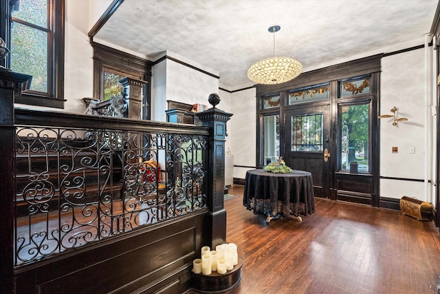 foyer with an inviting chandelier, crown molding, and hardwood / wood-style floors