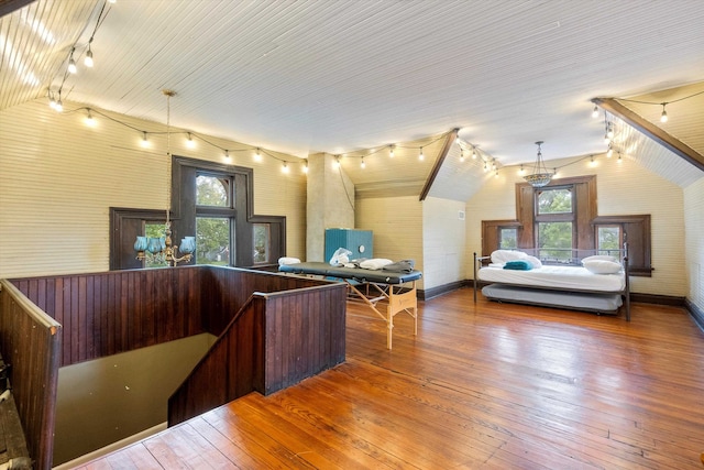 bedroom with multiple windows, lofted ceiling, and hardwood / wood-style floors