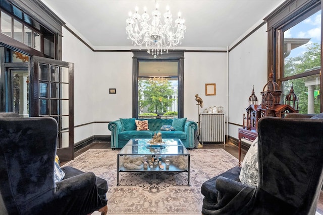 living room featuring radiator, wood-type flooring, ornamental molding, and a chandelier