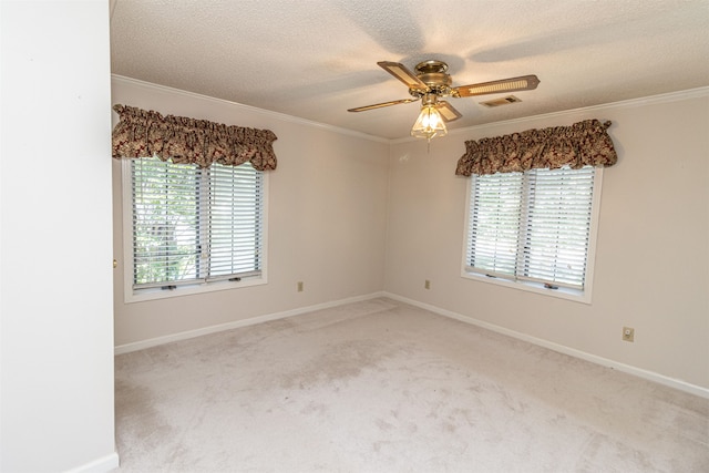 carpeted spare room with ceiling fan, a textured ceiling, ornamental molding, and a healthy amount of sunlight