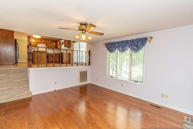 unfurnished living room with a textured ceiling, crown molding, light hardwood / wood-style floors, and ceiling fan with notable chandelier