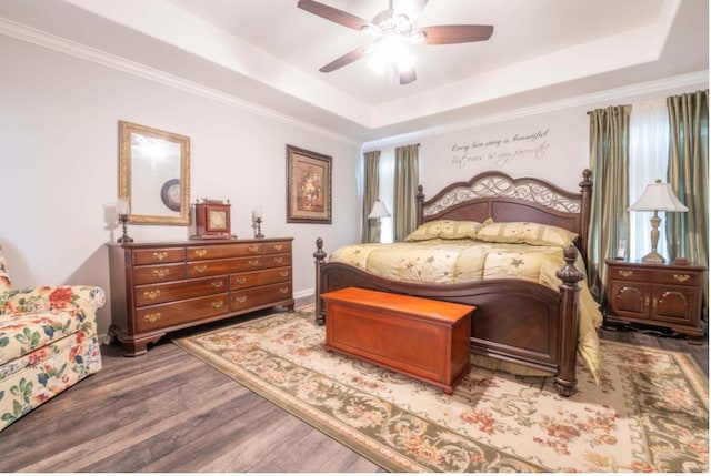 bedroom with ceiling fan, a raised ceiling, hardwood / wood-style floors, and crown molding