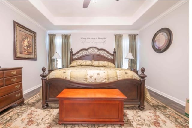 bedroom with ceiling fan, ornamental molding, a tray ceiling, and light hardwood / wood-style floors