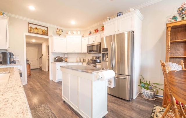 kitchen featuring appliances with stainless steel finishes, white cabinetry, light stone countertops, dark hardwood / wood-style flooring, and crown molding