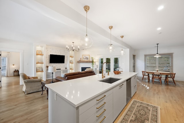 kitchen featuring an island with sink, light hardwood / wood-style flooring, hanging light fixtures, and sink