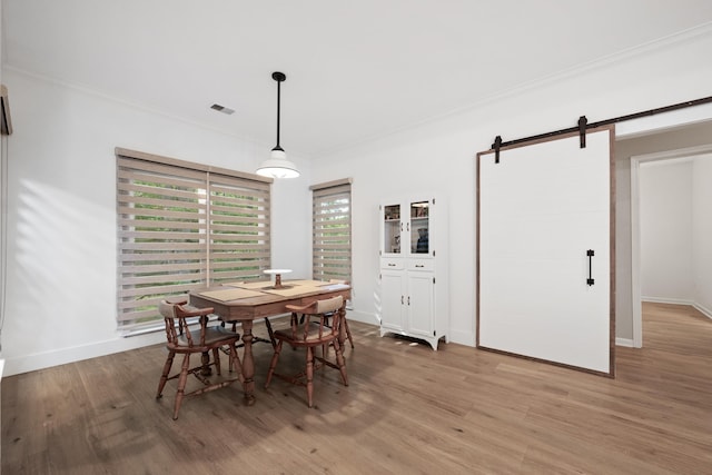 dining space with crown molding, hardwood / wood-style floors, and a barn door