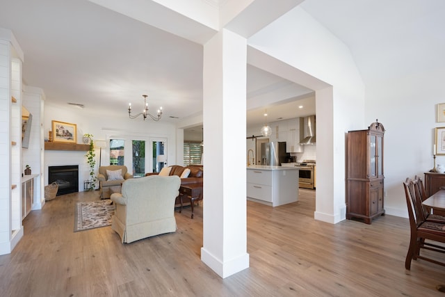 living room featuring light wood-type flooring, sink, and a notable chandelier