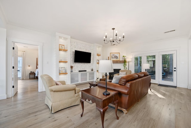 living room featuring light hardwood / wood-style flooring, an inviting chandelier, a fireplace, and crown molding