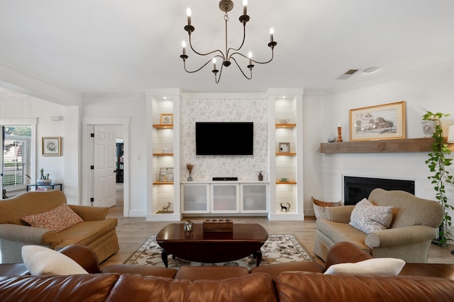 living room with ornamental molding, a notable chandelier, light hardwood / wood-style floors, and a large fireplace