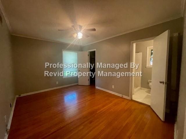 unfurnished bedroom featuring ensuite bathroom, ceiling fan, hardwood / wood-style flooring, and ornamental molding