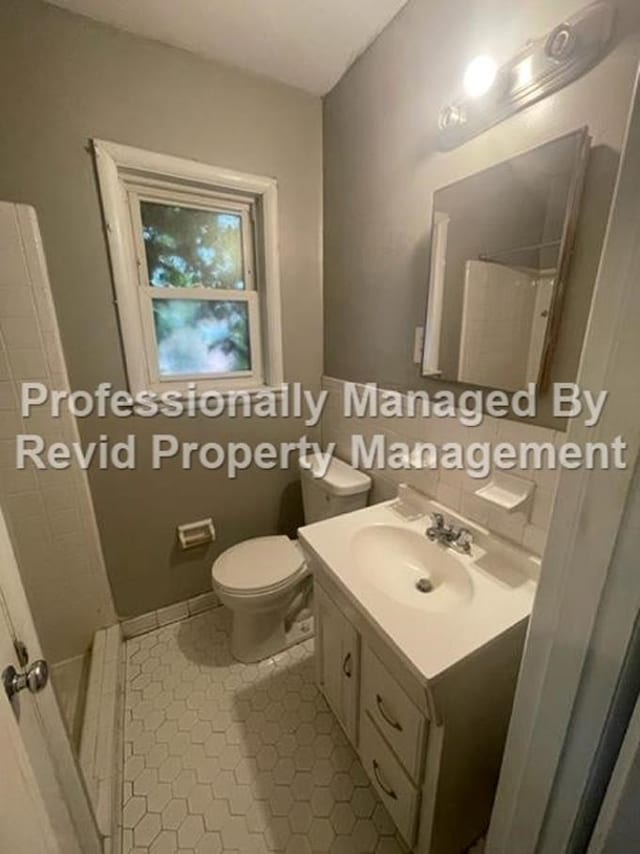 bathroom featuring toilet, tile patterned flooring, a shower, and vanity