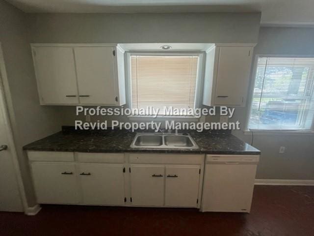 kitchen with white dishwasher, sink, and white cabinetry