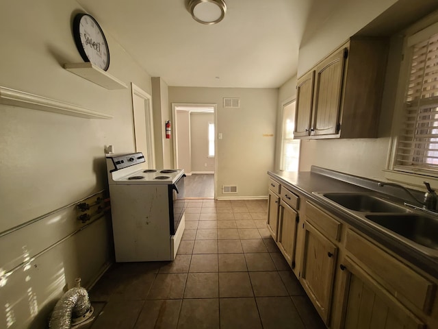 kitchen with dark tile patterned floors, electric range, and sink