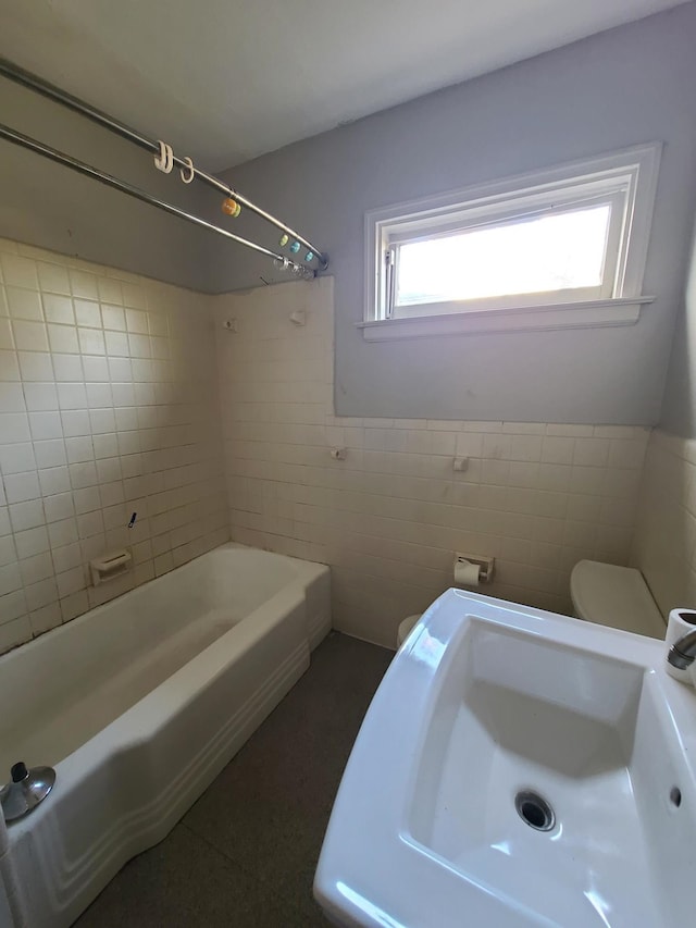 bathroom with tiled shower / bath combo, tile walls, and toilet