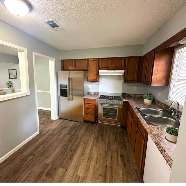 kitchen with a textured ceiling, premium appliances, sink, and dark hardwood / wood-style flooring