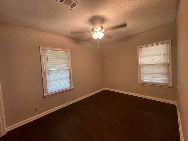 unfurnished room with a textured ceiling, dark wood-type flooring, and ceiling fan