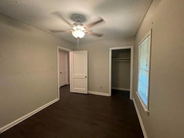 unfurnished bedroom featuring multiple windows, dark hardwood / wood-style floors, ceiling fan, and a closet