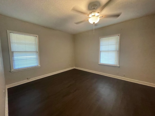 empty room featuring ceiling fan, a textured ceiling, and dark wood-type flooring