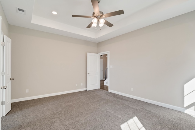 unfurnished room with carpet, a tray ceiling, and ceiling fan