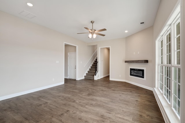 unfurnished living room featuring ceiling fan and dark wood-type flooring