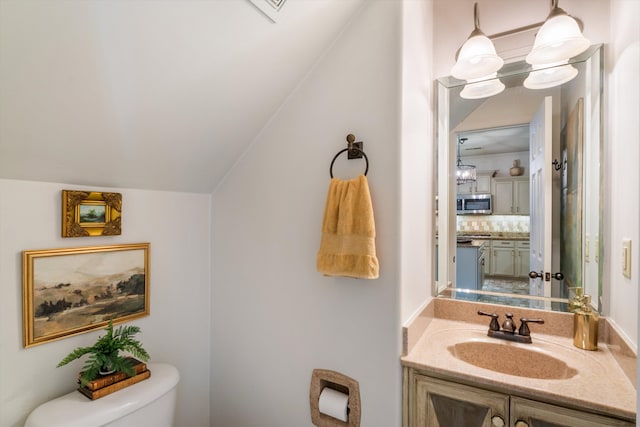 bathroom featuring backsplash, vanity, lofted ceiling, toilet, and a notable chandelier