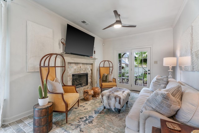 living room featuring a brick fireplace, ceiling fan, and crown molding