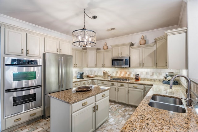 kitchen featuring hanging light fixtures, light stone counters, backsplash, stainless steel appliances, and sink