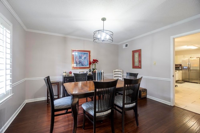 dining room featuring a notable chandelier, a textured ceiling, crown molding, and dark hardwood / wood-style flooring