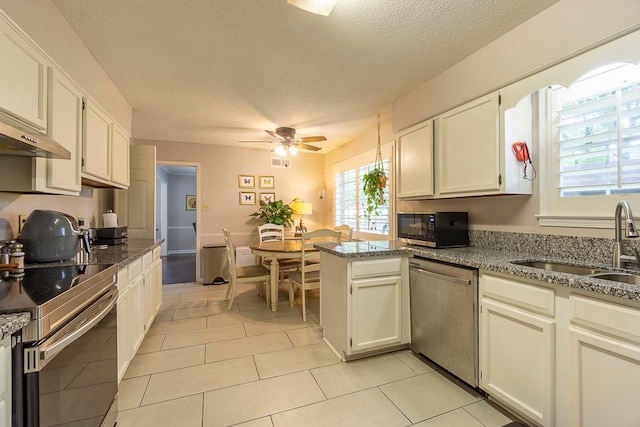 kitchen featuring a textured ceiling, white cabinetry, stainless steel appliances, and light stone counters