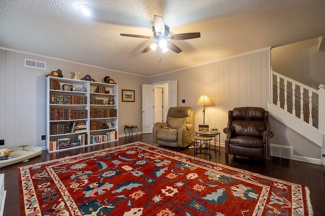 sitting room featuring ceiling fan, ornamental molding, a textured ceiling, wooden walls, and dark hardwood / wood-style floors