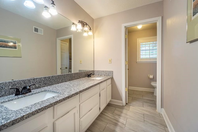 bathroom with vanity, toilet, and a textured ceiling