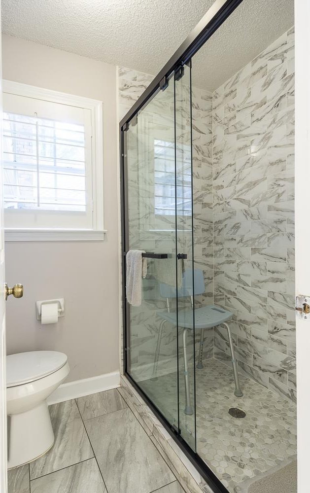 7150 Woodridge Ln, Germantown, TN 38138 - full bathroom with a textured ceiling, toilet, a stall shower, baseboards, and marble finish floor