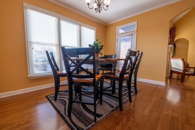 dining area featuring an inviting chandelier, dark hardwood / wood-style floors, crown molding, and a wealth of natural light