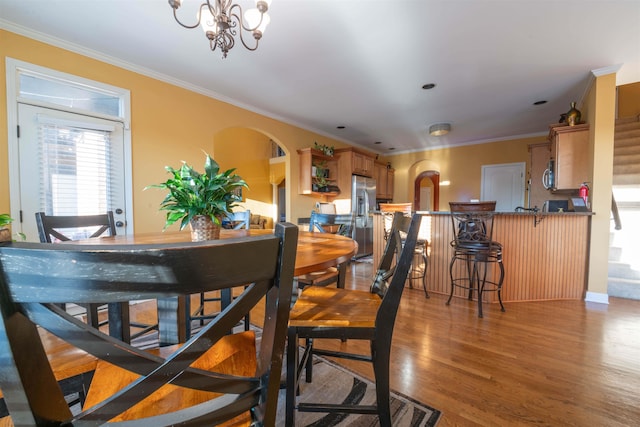 dining area featuring ornamental molding, dark wood-type flooring, and a notable chandelier