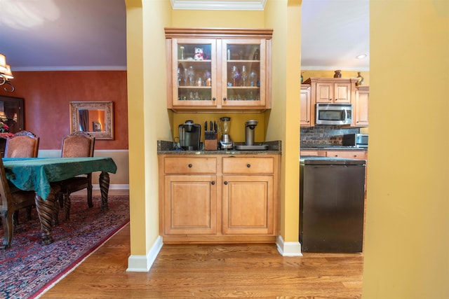 kitchen with decorative backsplash, light hardwood / wood-style floors, crown molding, and dark stone countertops