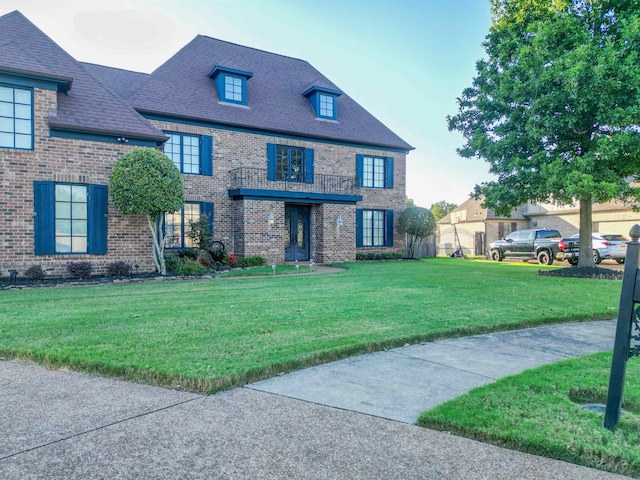 view of front of property featuring a balcony and a front lawn