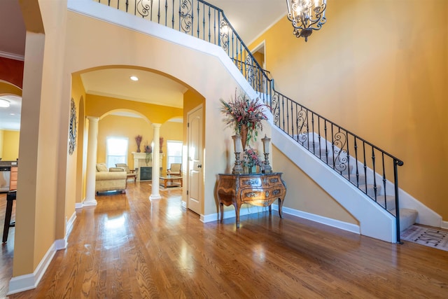 entryway with ornamental molding, hardwood / wood-style flooring, a towering ceiling, and decorative columns