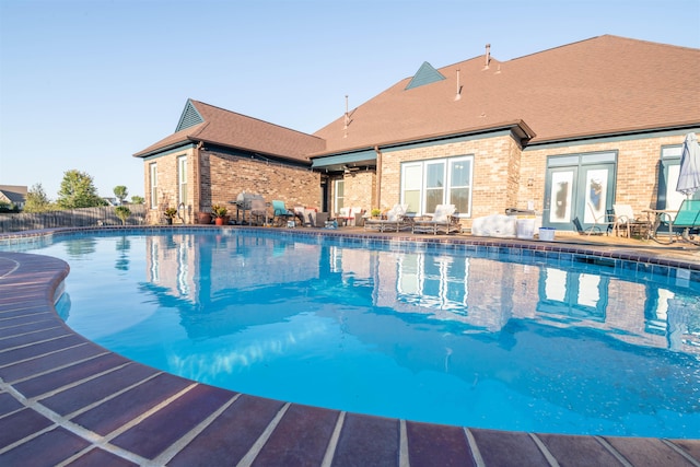 view of swimming pool featuring french doors and a patio area