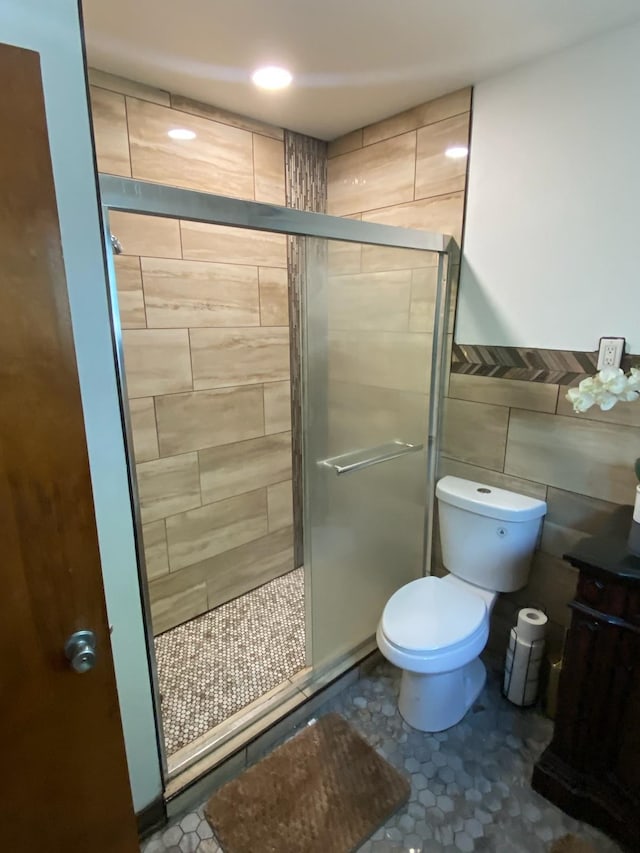 bathroom with tile walls, walk in shower, tile patterned floors, and toilet